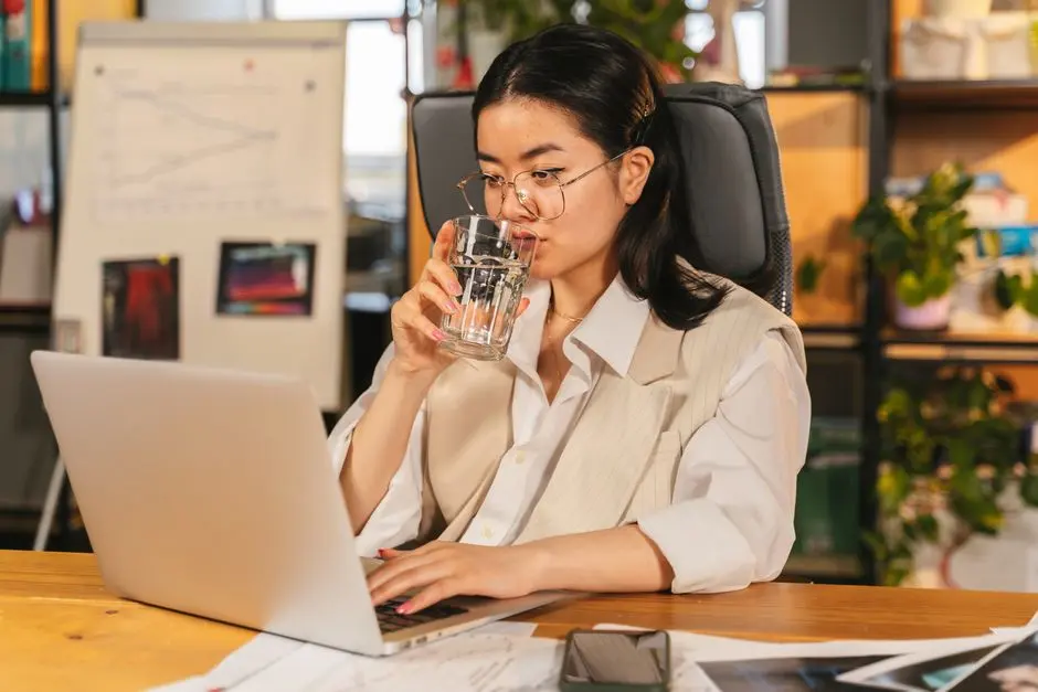 Pekerja kantor minum air dan melakukan peregangan ringan di meja kerja